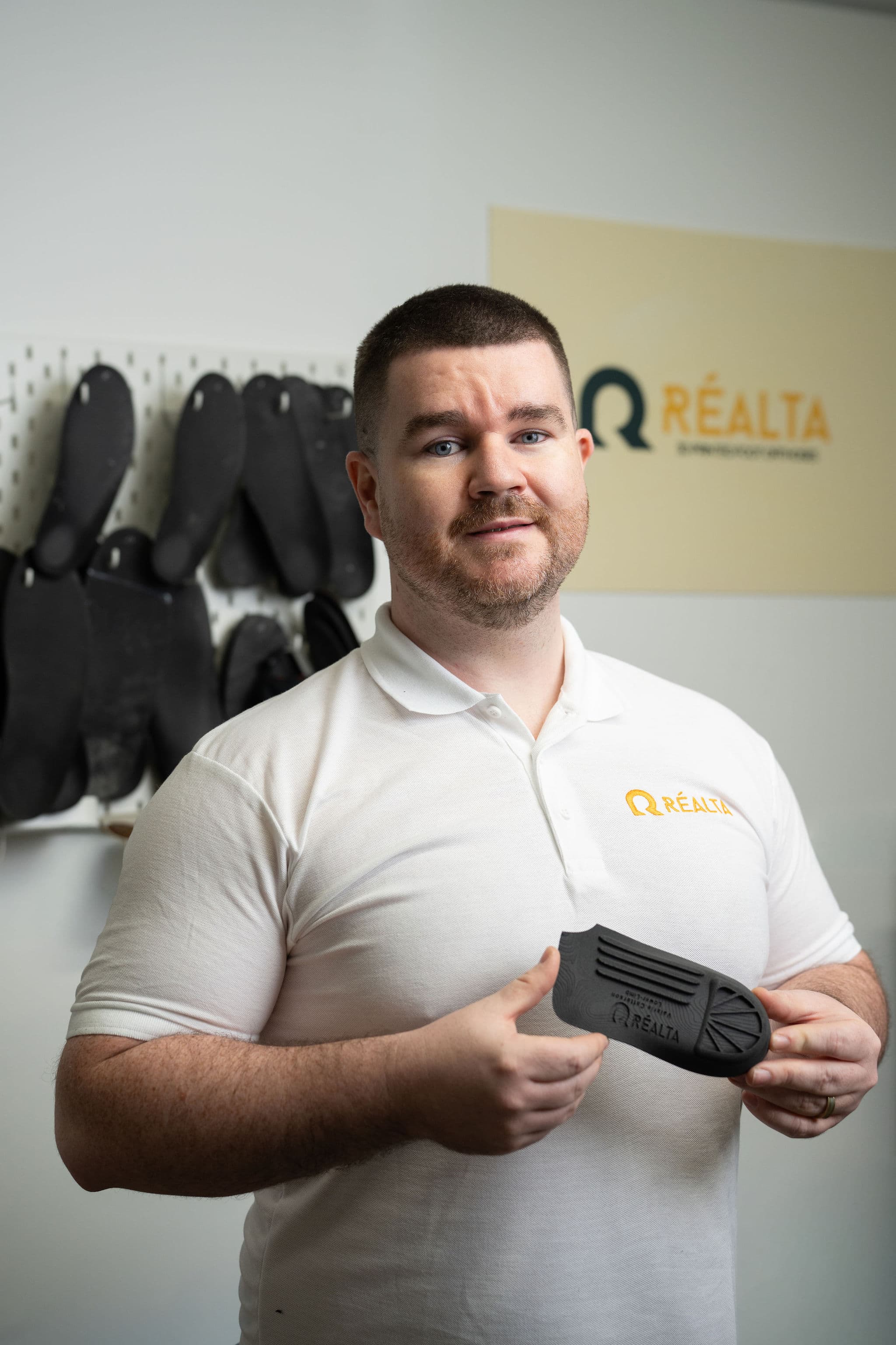 Paul McMullan, founder of Réalta Labs, holding an orthotic shell with Réalta sign behind